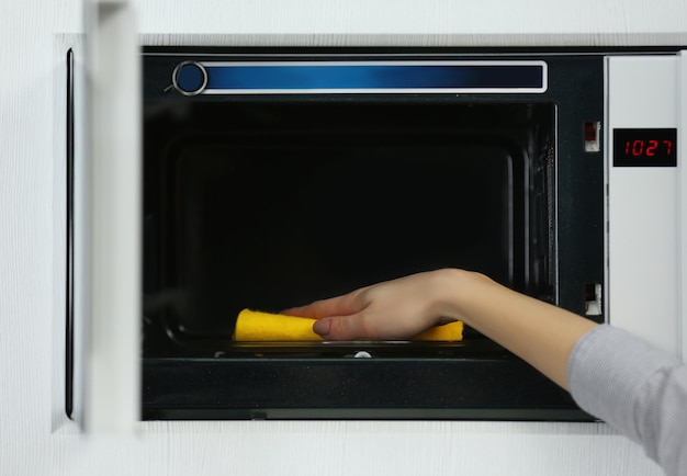 Vrouwelijke handreinigende magnetron met een spons