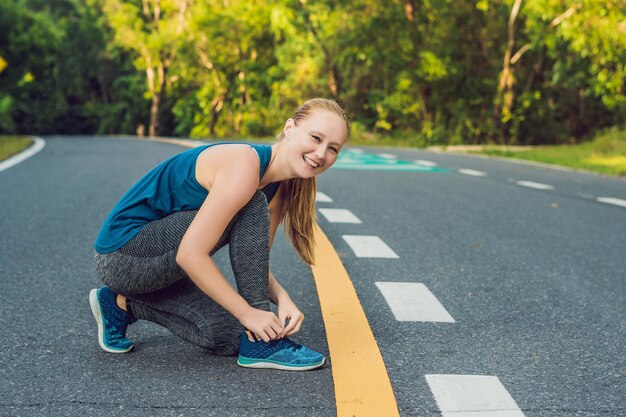 Vrouwelijke hardloper die haar schoenen bindt en zich voorbereidt om buiten te joggen. Jonge girld runner maakt zich klaar voor training. Sportieve levensstijl