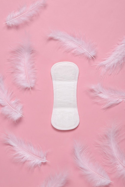 Vrouwelijke hygiëne concept menstruatie gynaecologische zachte pad en veren op roze achtergrond