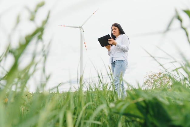 Vrouwelijke ingenieur aan het werk op het windturbinepark met tablet