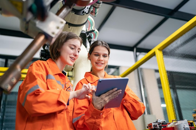 Vrouwelijke ingenieur controle en controle automatisering robotarmen machine in intelligente industriële fabriek op real-time bewakingssysteem software robotica en digitale productie