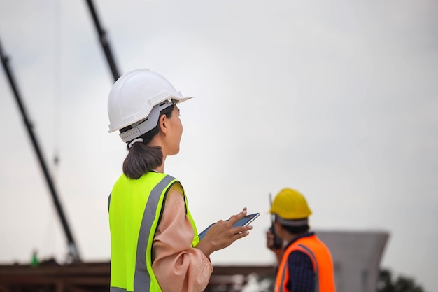 Vrouwelijke ingenieur en voorman werknemer controleren project op bouwplaats ingenieur en bouwers in veiligheidshelmen bespreken op bouwplaats teamwork concepten