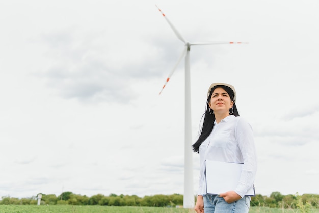 Vrouwelijke ingenieur met harde hoed aan het werk op het windturbinepark