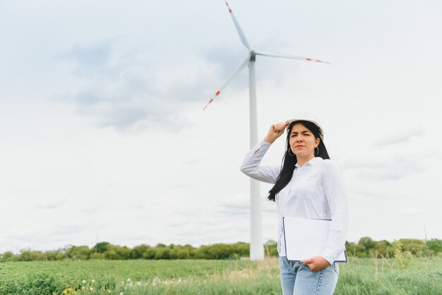 Vrouwelijke ingenieur werken en houden het rapport bij windturbineboerderij Power Generator Station op de berg
