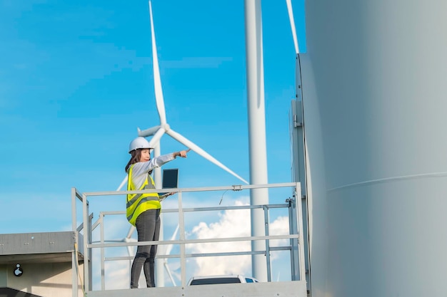 Vrouwelijke ingenieur werkt en houdt het rapport vast bij het power generator station van het windturbinepark op mensen uit bergthailand