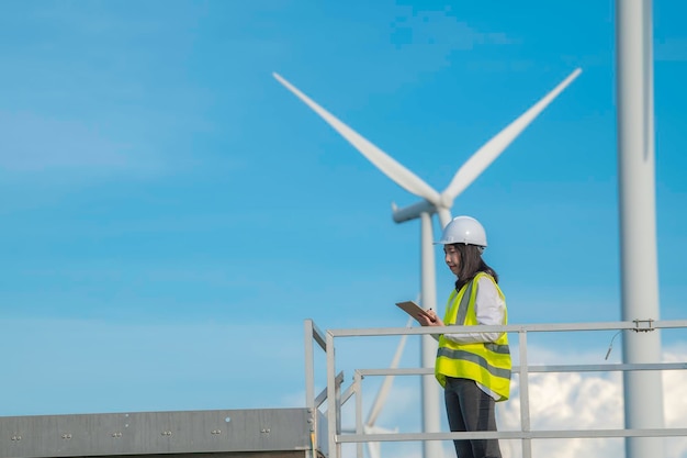 Vrouwelijke ingenieur werkt en houdt het rapport vast bij het Power Generator Station van het windturbinepark op mensen uit bergThailand