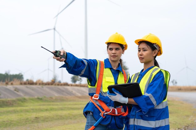 Vrouwelijke ingenieur wijst en houdt tablet inspectie en onderhoud van windturbines in windparken