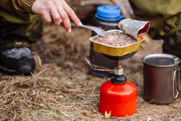 Vrouwelijke jager die voedsel bereidt met een draagbare gasbrander in een winterbos