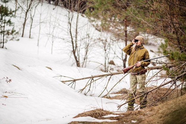 Vrouwelijke jager in camouflagekleding klaar om te jagen met pistool en wandelen in het bos