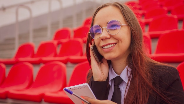 Vrouwelijke journalist die op smartphone spreekt en wedstrijden bespreekt in het straatstadion