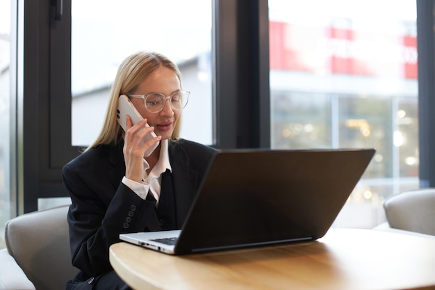 Vrouwelijke kantoormedewerker die typt en contact maakt met klanten