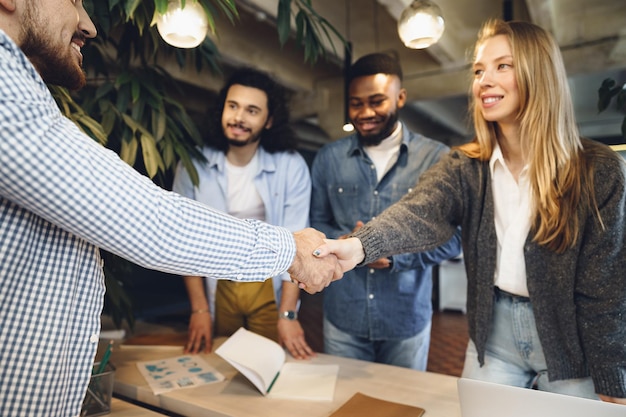 Foto vrouwelijke kantoormedewerker schudt de hand van een nieuwe mannelijke medewerker van het teamlid