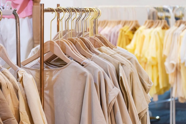 Vrouwelijke katoenen kleding in neutrale toon hangend aan kledingrek te koop in boetiekmodewinkel