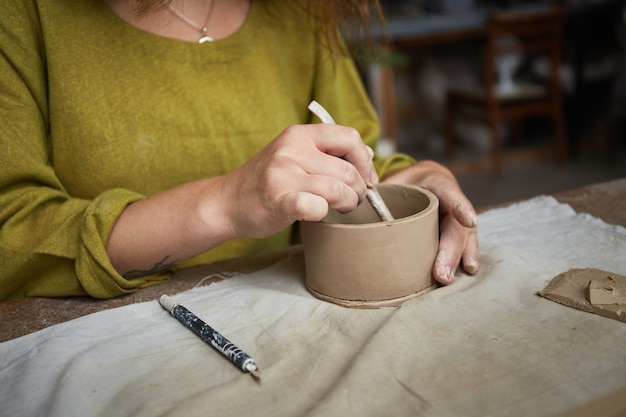 Vrouwelijke keramist die in aardewerkstudio werkt. Keramistenhanden Vuil Van Klei. Proces van het maken van aardewerk. Meesterkeramist werkt in haar atelier