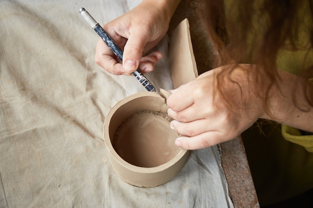 Vrouwelijke keramist die in aardewerkstudio werkt. Keramistenhanden Vuil Van Klei. Proces van het maken van aardewerk. Meesterkeramist werkt in haar atelier