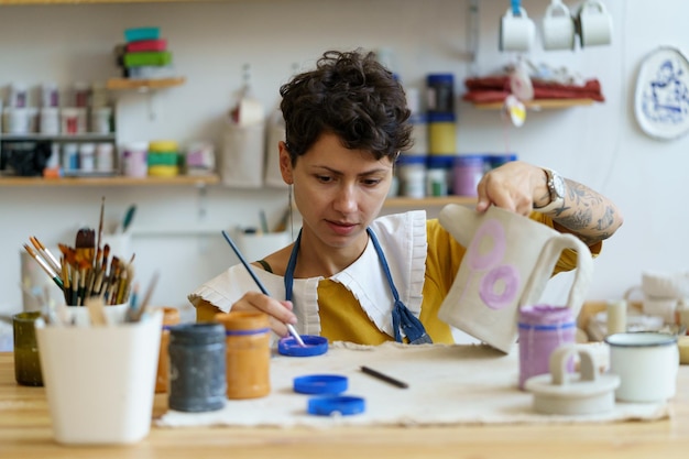 Vrouwelijke keramist tekening ornament op klei theepot vrouw pottenbakker meester aardewerk in studio schilderen