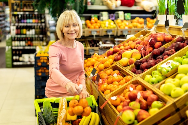 Vrouwelijke klant die bij supermarkt koopt die fruit kiest