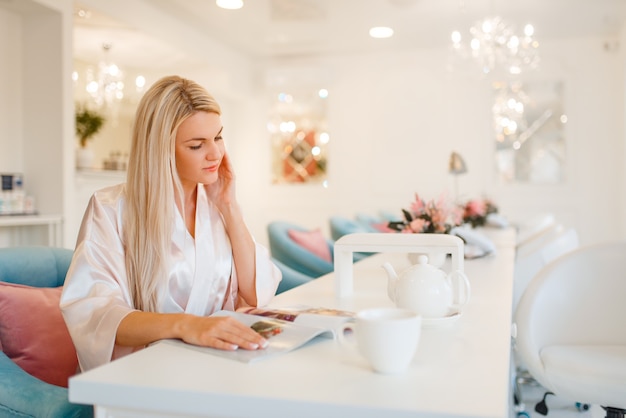 Vrouwelijke klant drinkt koffie in de schoonheidssalon.