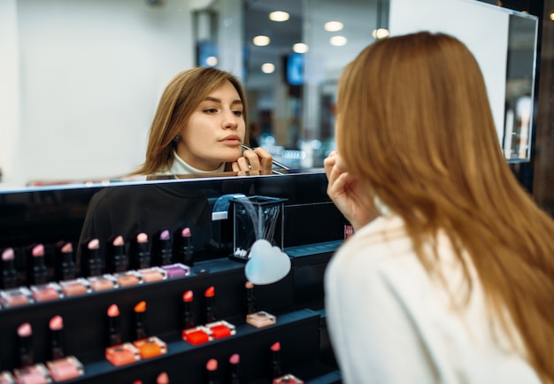 Vrouwelijke klant lip voering in de make-up shop testen. Cosmetica kiezen in schoonheidssalon, make-up salon