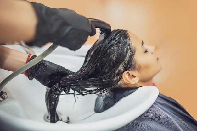 Vrouwelijke klant wast haar in salon professionele kapper wast hoofd van vrouwelijke klant met water en shampoo behandeling kapsel schoonheid haarverzorging mode service