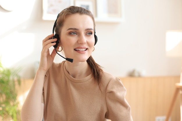 Vrouwelijke klantenondersteuningsoperator met hoofdtelefoon en glimlachen.