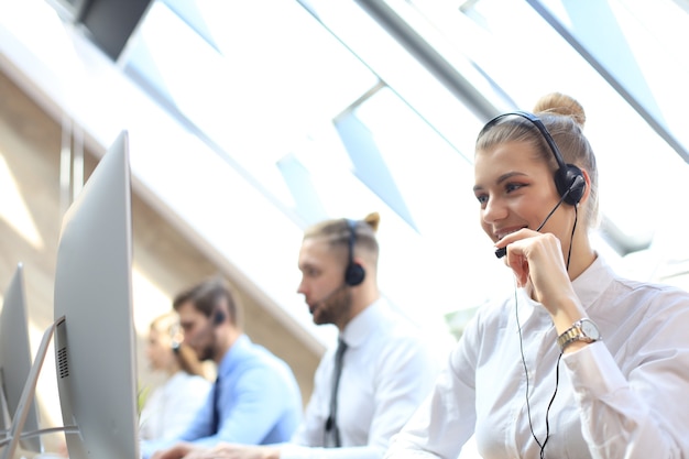 Vrouwelijke klantenondersteuningsoperator met hoofdtelefoon en glimlachen.