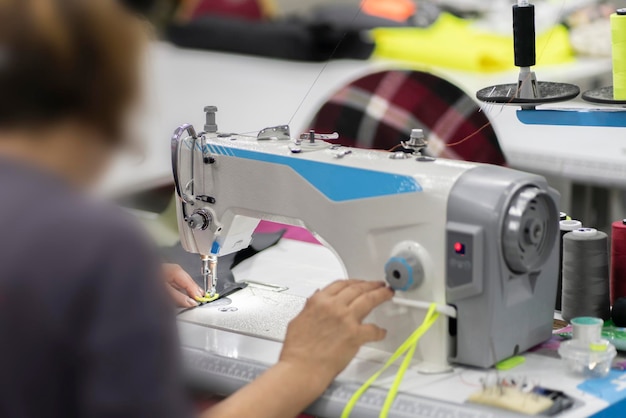 vrouwelijke kleermaker die op de fabriek werkt met behulp van een naaimachine close-up shot