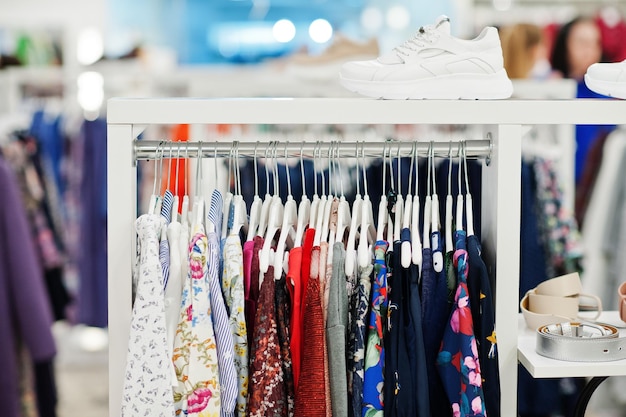 Vrouwelijke kleurrijke kledingset op de rekken met schoenen in de gloednieuwe moderne boetiek van de kledingwinkel