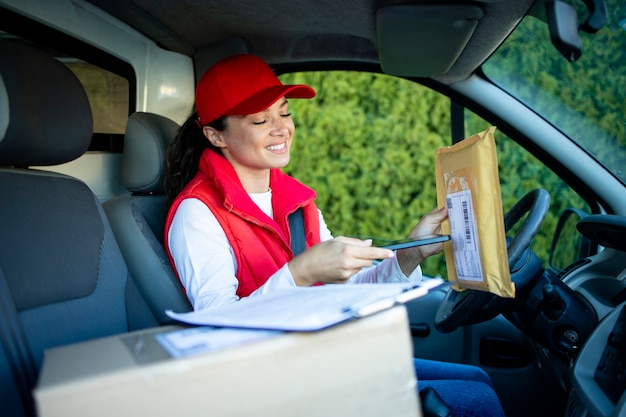 Vrouwelijke koerier in bestelwagen die pakketten scant voordat de zending wordt afgeleverd.