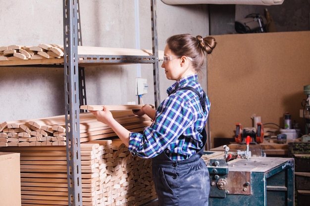 Vrouwelijke leerling die houten plank controleert bij timmerwerkplaats