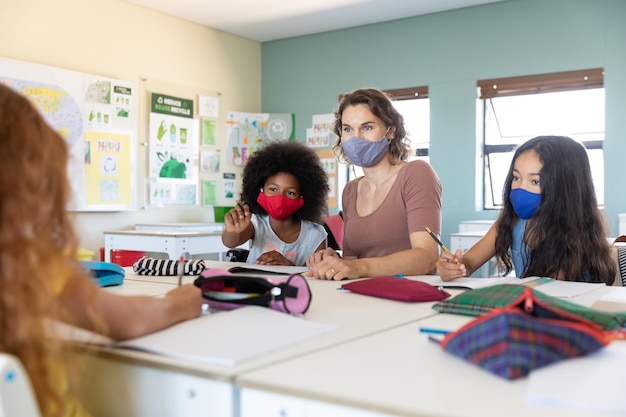 Vrouwelijke leraar en twee meisjes met gezichtsmasker in de klas