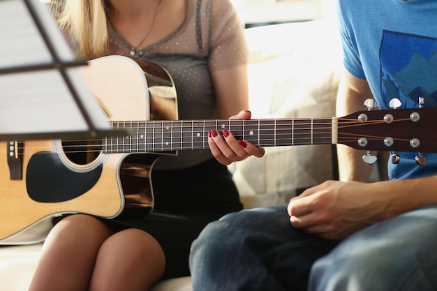 Vrouwelijke leraar legt thuis notities uit aan de klant over de muziekles van het gitaarinstrument