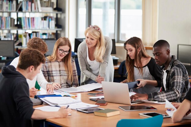 Vrouwelijke Leraar Werken Met Studenten In Bibliotheek