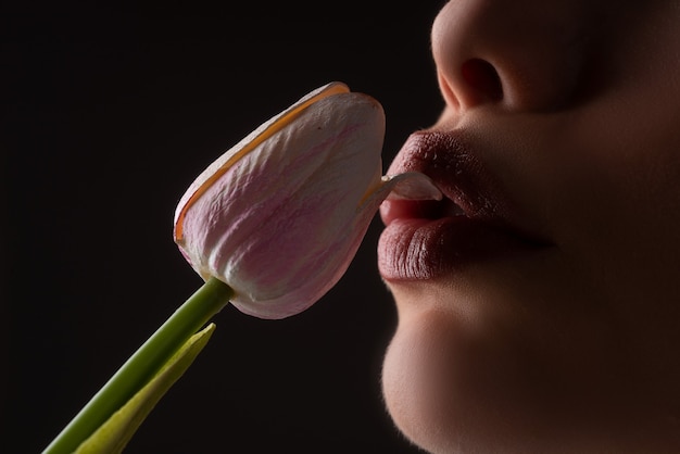 Vrouwelijke lippen en lentebloem. Sexy vrouw mond en bloemen. Orale seks, orgasme, pijpbeurt, bloem likken. Meisjeslippen met tulpen.