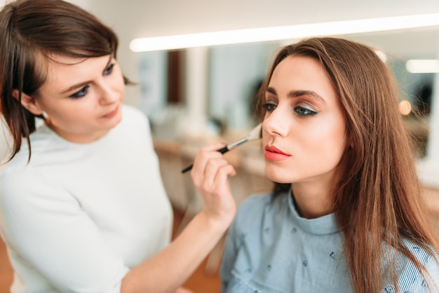 Vrouwelijke make-up artiest werken met vrouw gezicht