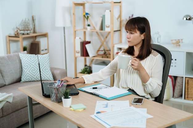 vrouwelijke manager die een mok vasthoudt, controleert haar schema op het notitieboekje. serieuze knappe supervisor bekijkt een rapport terwijl ze haar dagelijkse koffie drinkt.