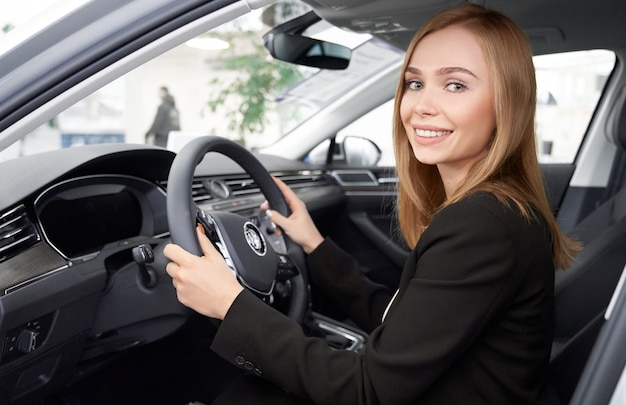 Vrouwelijke manager van dealershipzitting in de zetel van de autobestuurder.