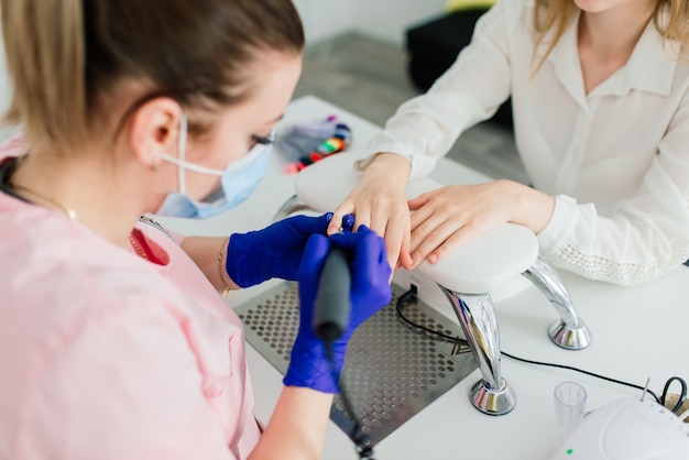 Vrouwelijke manicure meester in een schoonheidssalon werken met de handen van de klant