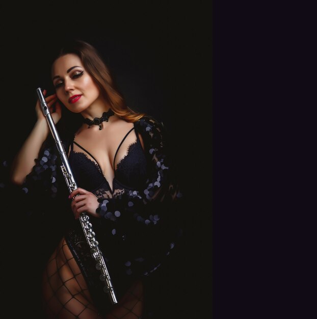 Vrouwelijke meisjeskunstenaar in pak met fluit op zwarte achtergrond