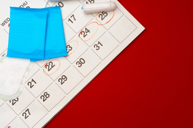 Vrouwelijke menstruatiekalender en hygiënische pads bovenaanzicht kopie ruimte