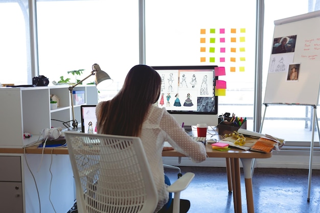 Vrouwelijke modeontwerper die aan het bureau werkt in een modern kantoor