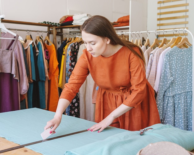 Vrouwelijke modeontwerper markeert materiaal met een stuk zeep voor het naaien van kleding