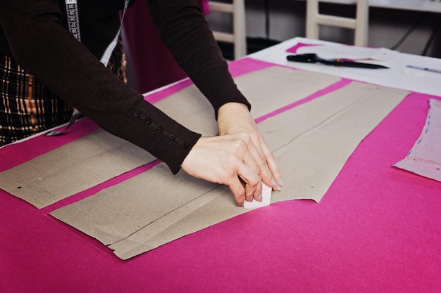 Vrouwelijke modeontwerper op maat naaipatronen maken op de werkplek in naaiatelier naaister