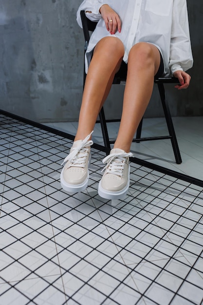 Vrouwelijke mooie benen in beige casual sneakers Stijlvolle leren zomerschoenen voor dames