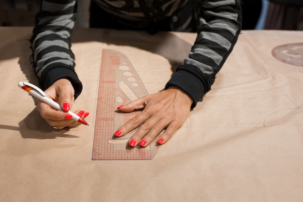 Vrouwelijke naaister handen kleermaker tekenen op Kraft papier voor het maken van patronen