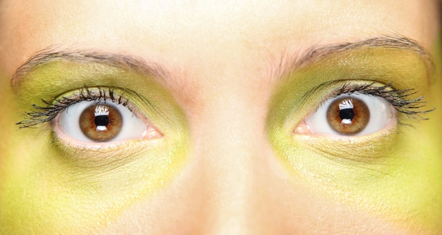 Foto vrouwelijke ogen geschilderd in groen over groene achtergrond