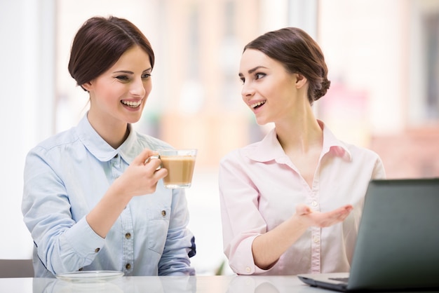 Vrouwelijke ondernemers zitten in stedelijke café en het gebruik van laptop.