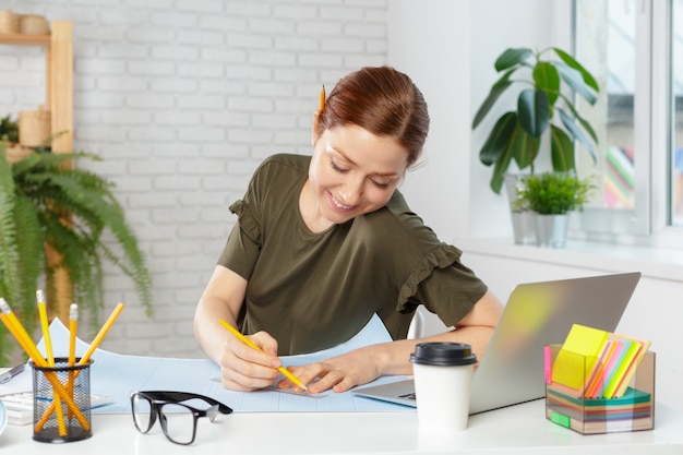 Vrouwelijke ontwerper in bureau die aan architectenproject werken