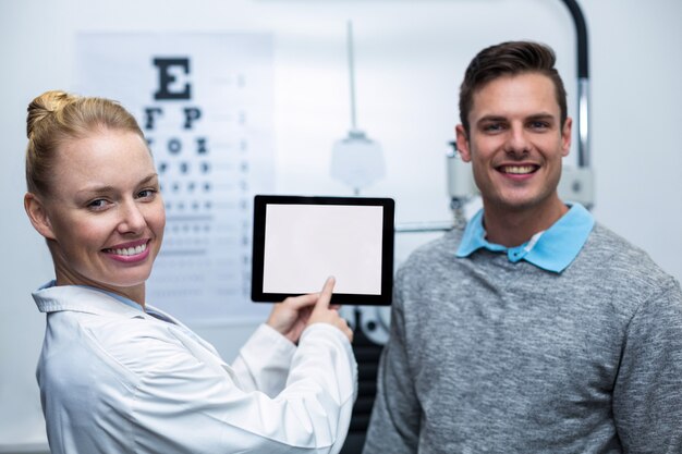 Vrouwelijke optometrist die bespreking met patiënt op digitale tablet heeft