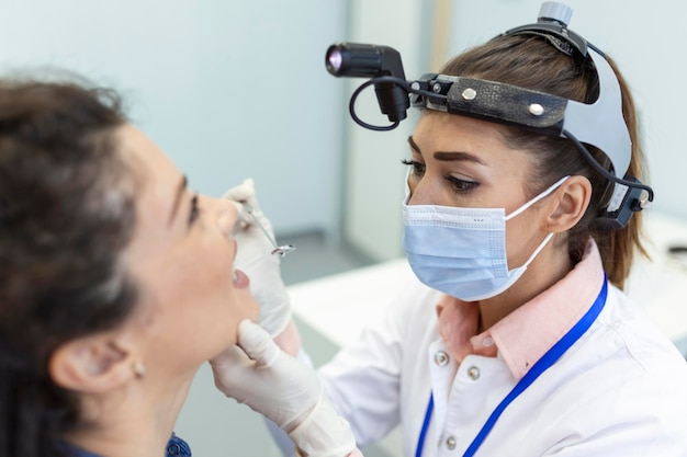 Vrouwelijke patiënt die haar mond opent zodat de dokter in haar keel kan kijken Otolaryngoloog onderzoekt keelpijn van patiënt